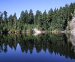 The reflection off of the calm water of Mystery Lake in Mount Seymour Provincial Park