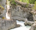 The water spills over Nairn Falls and passes between the rocky canyon